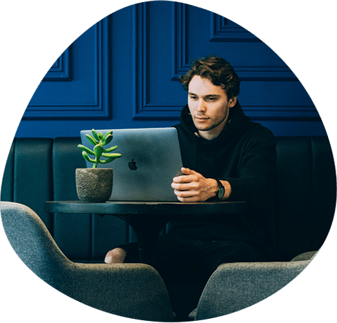 A cutout of a young man working on a laptop, seated in a stylish blue interior