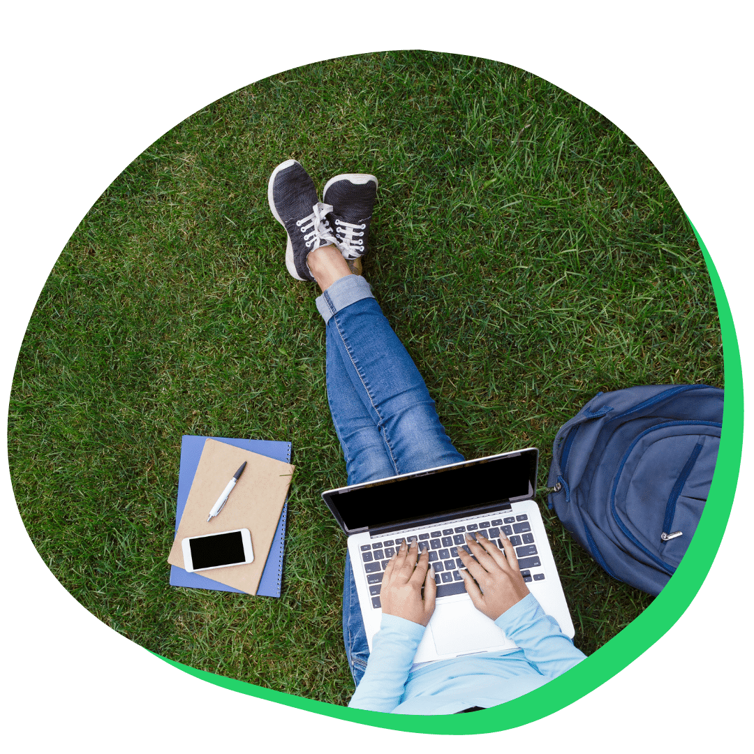 Student doing work in the grass on campus